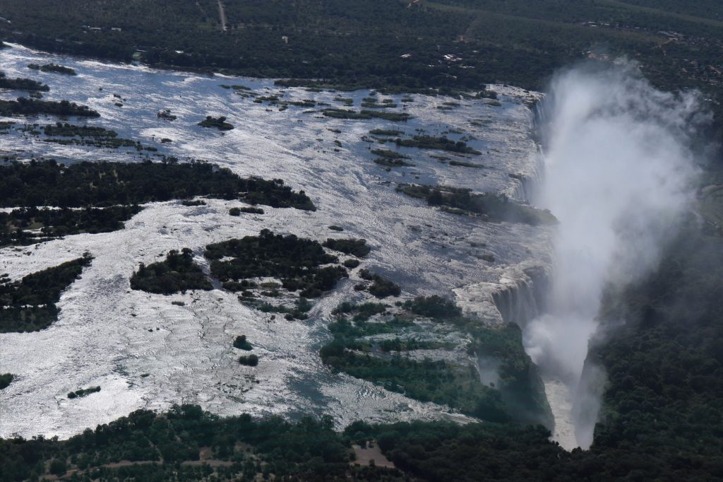 A stunning image of the sunlight reflecting off the Zambezi River's water before plunging over Victoria Falls and into the gorge in a spray of mist, Flight of Angels