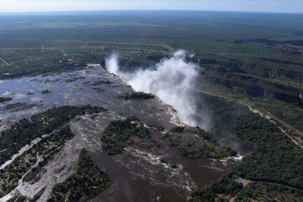 Flying in a helicopter over the Zambezi River heading towards the drop and spray of the Victoria Falls