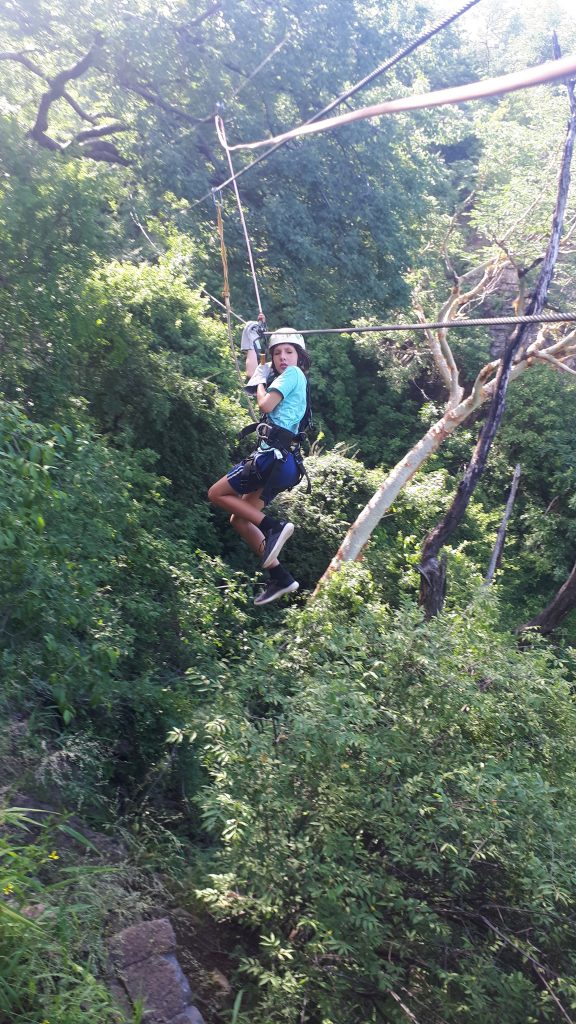 Cadan zipping down a line in the middle of the stunning forest