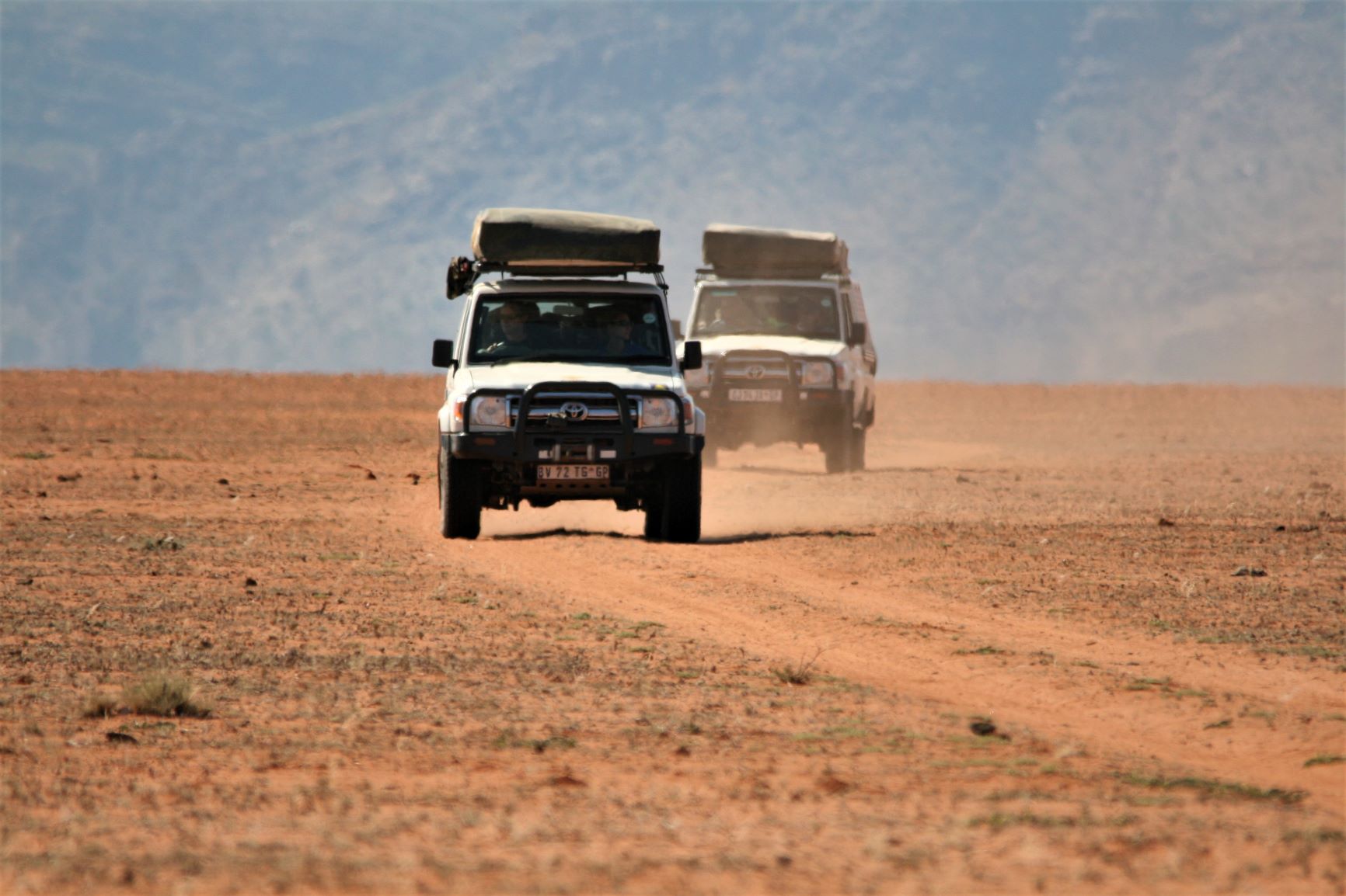 Two four wheel drive self drive vehicles drive towards the camera in the Kunene region, Namibia