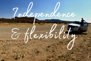 The words 'independence & flexibility' set over a self drive vehicle on a road in the desert landscape of Namibia