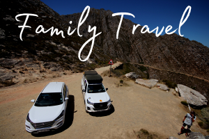 The word 'family travel' set over an imagine of two self drive vehicles at the top of a pass near Cape Town, South Africa